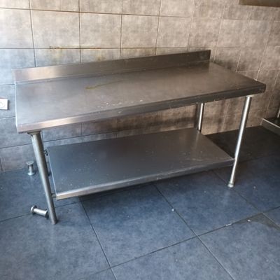 a stainless steel table in the middle of a tiled room