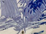 a blue and white plate with a woman and a dog on it