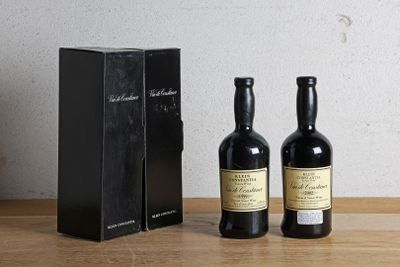 deux bouteilles de vin posées à côté d'une boîte noire sur une table en bois