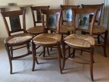 four wooden chairs with wicker seats in the middle of a room