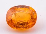 a yellow sapphire stone on a white surface