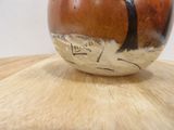 a brown and black vase sitting on a wooden table