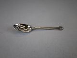 silver spoon with a spoon handle on a gray surface