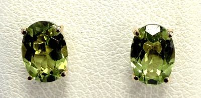 a pair of earrings with green stones sitting on top of a white surface