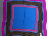 un gros plan sur une écharpe carrée violette et bleue posée sur une table