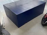 une boîte bleue posée par terre à côté d'un scooter