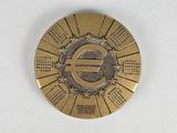 a gold medal with a symbol on it on a white surface