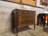 a wooden chest of drawers in a room with a mirror