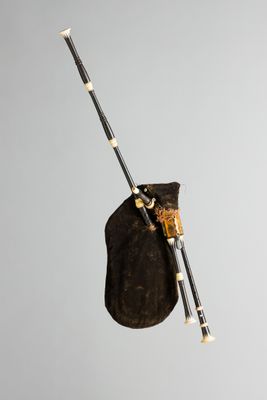 une image représentant une cornemuse avec un sac et deux baguettes