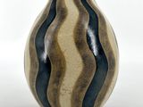 un vase rayé noir et blanc posé sur une surface blanche