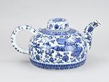 a blue and white teapot with a bird design on it