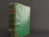 an old green book sitting on top of a black table