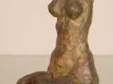 statue of a woman sitting on a rock on a glass table
