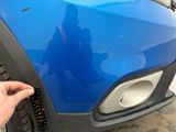 a hand that is holding a stick to a car ' s bumper