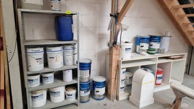 several buckets of paint on the shelves in the garage