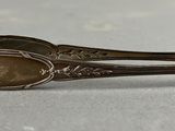 une cuillère ancienne au manche doré posée sur une surface blanche
