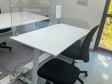 a white desk with two black chairs and a computer on it