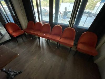several orange chairs are lined up in a row in front of a window