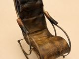 fauteuil à bascule en cuir marron posé sur une surface blanche