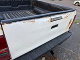 a white truck that has rust on the back of it