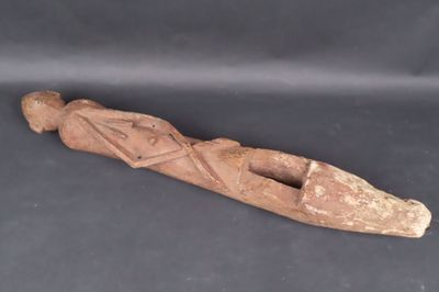 une vieille statue en bois représentant une personne allongée sur une surface noire