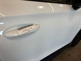 the door handle of a white car with a sticker on it