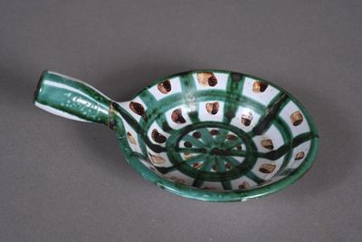 a green and white bowl with a spoon in it