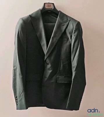 black jacket hanging on a hanger against a white wall