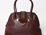 brown leather handbag with brass hardware on top of it