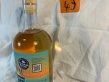 a bottle of alcohol sitting on a bed next to a pillow