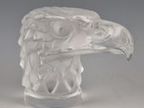 une sculpture en verre représentant une tête d'aigle, posée sur une table