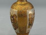 a gold vase with a painting on it on a gray surface