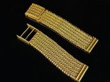 a pair of gold metal bracelets on a black surface