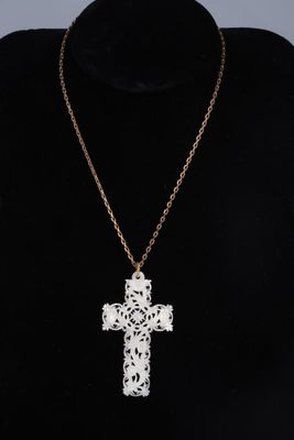 a white cross pendant on a gold chain on a mannequin mannequin mannequin mannequin mannequin mannequin mannequin mann