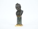 un buste en bronze représentant un homme, posé sur un socle en marbre
