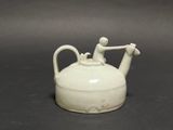a small white teapot with a man on top of it