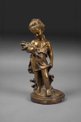 une statue en bronze représentant un garçon tenant un oiseau, posée sur un socle