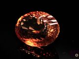 a close up of a large orange diamond on a black surface