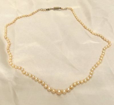a close up of a pearl necklace on a white cloth