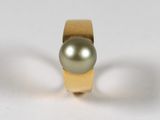 bague en or avec une perle au centre, sur un fond blanc
