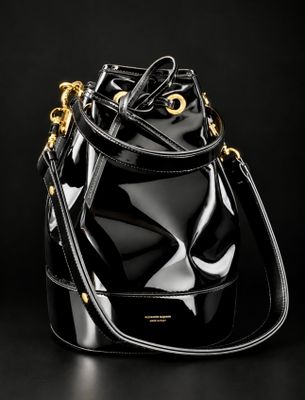 a black bucket bag with gold hardware on a black background