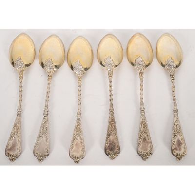 six silver spoons are lined up in a row on a white surface