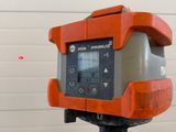 an orange and gray device on a tripod in front of a white wall