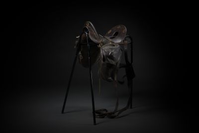 a horse saddle on a stand in a dark room
