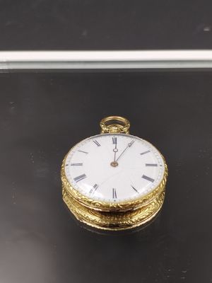 une montre de poche en or posée sur une surface noire