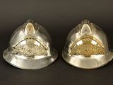 pair of silver helmets with gold emblems on them on a black background