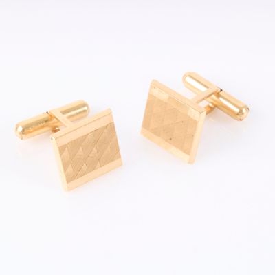 a pair of gold cufflinks on a white background