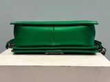 the green purse is sitting on top of a white box