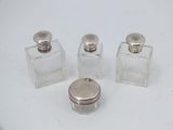 three small glass bottles with silver lids sitting on a white surface