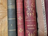 several old books are lined up on a shelf in a bookcase